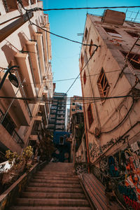 Low angle view of steps amidst buildings against sky