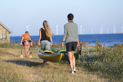 Mother with daughter carrying kayaks