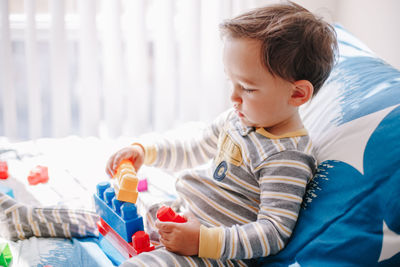 Cute baby toddler playing building with learning toy stacking blocks at home. early age education