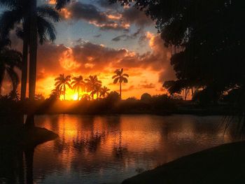 Silhouette trees by lake against sky during sunset