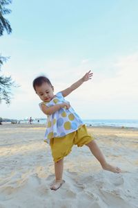 Full length of girl standing at beach against sky