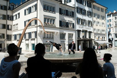 People in town square against sky in city