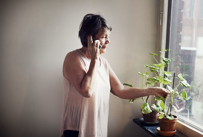 Woman standing by potted plant at home