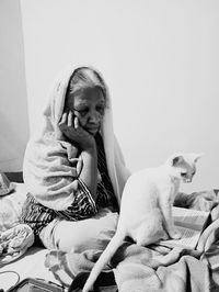 Woman with dog sitting against wall