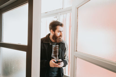 Young man using phone by door