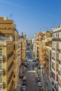 Vehicles on street amidst buildings against sky in city