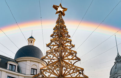 Wooden christmas tree against rainbow at christmas market in the city