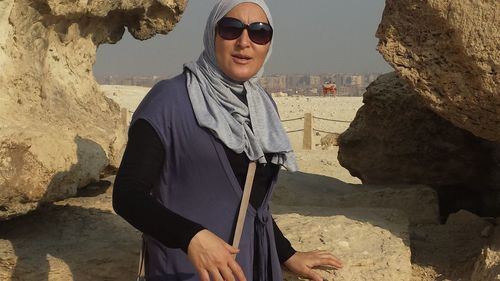 Portrait of woman standing against rock