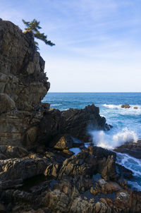 Rock formation on beach against sky