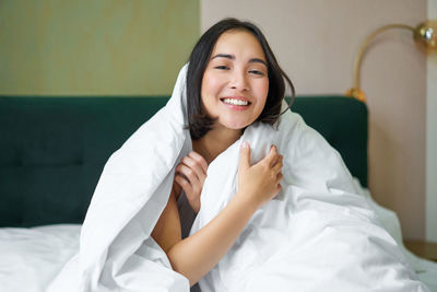 Portrait of young woman with arms crossed standing on bed