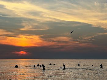 Silhouette people at beach against sky during sunset