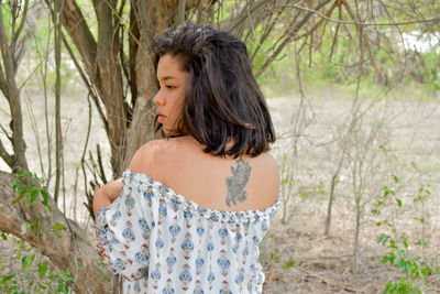 Side view of woman standing in forest