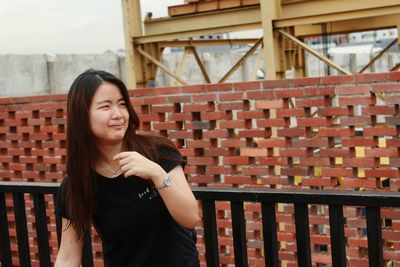 Beautiful young woman standing against wall