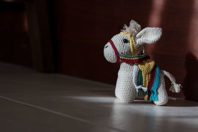 Close-up of knitted donkey toy on tiled floor at home