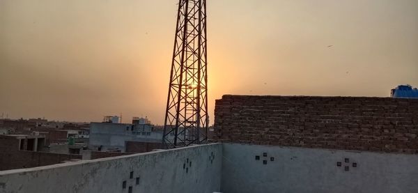 Construction site by buildings against sky during sunset