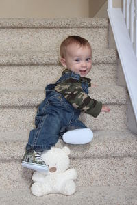 Full length portrait of cute boy with toy on steps