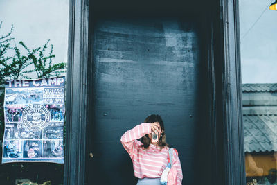 Woman photographing while standing against closed door