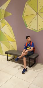 Boy sitting on floor against wall