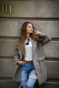 Beautiful young woman sitting on staircase against wall
