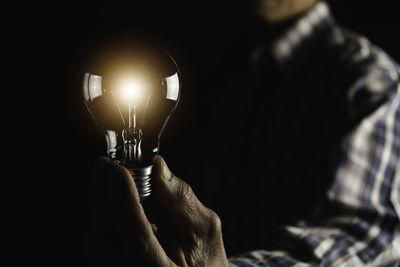 Close-up of hand holding illuminated light bulb