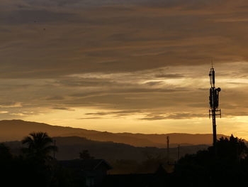 Silhouette of communications tower against sky during sunset