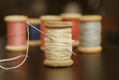 Close-up of sewing needle and spool of thread on table