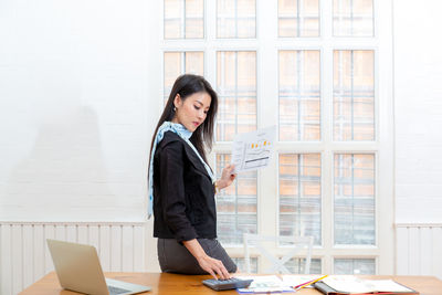 Young woman using mobile phone while standing on table