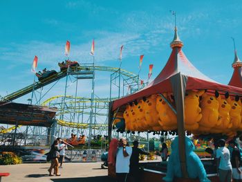 People at amusement park against sky