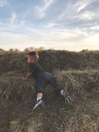 Portrait of boy standing on field against sky