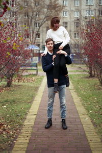 Full length of man carrying girlfriend on shoulders in park