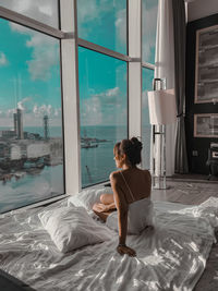 Woman sitting on bed in bedroom