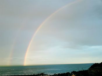 Scenic view of rainbow over sea against sky