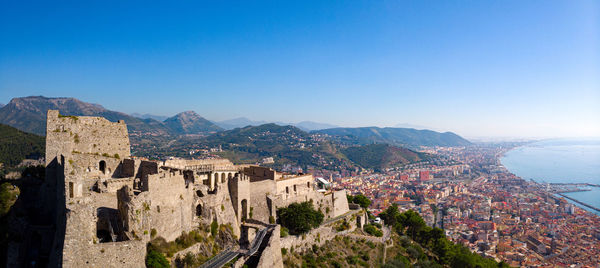 Panoramic view of buildings in city against clear blue sky