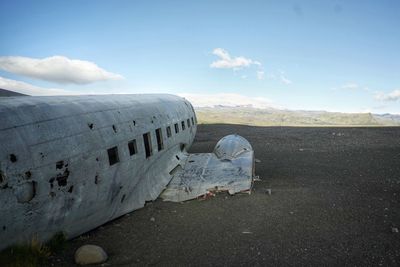 Crashed airplane at beach against sky