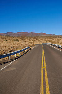 Empty road against clear blue sky