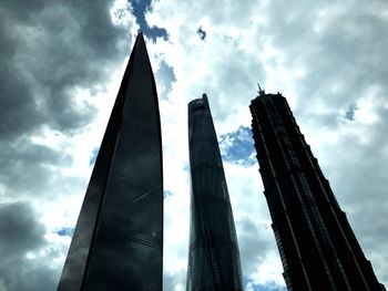 Low angle view of modern buildings against cloudy sky