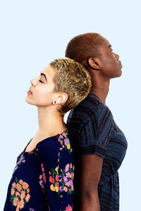 Lesbian couple standing back to back against white background