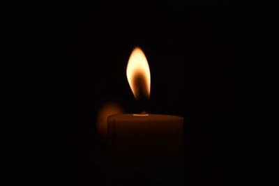 Close-up of lit candle against black background