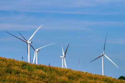 Windmills on field against sky