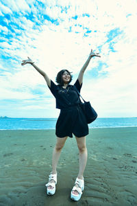 Full length of young woman at beach against sky