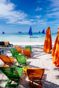 Empty lounge chairs at beach against sky