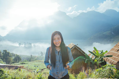 Portrait of young woman standing on mountain against sky