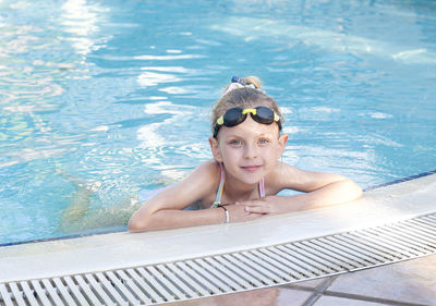 Little girl in swimming goggles swims in the pool