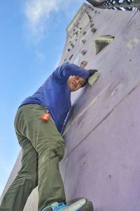 Low angle view of man standing against blue sky
