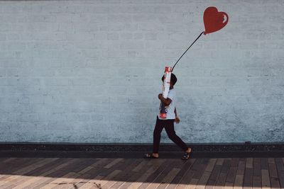 Full length of woman with umbrella standing on footpath