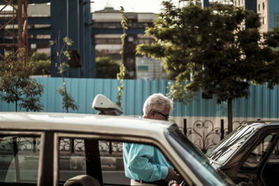 Man standing by car against buildings