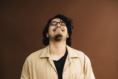 Cheerful man with eyes closed against brown background