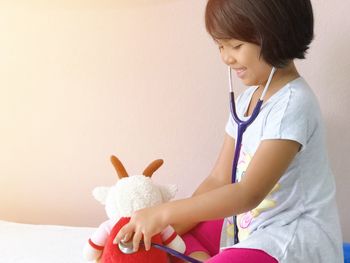 Happy girl holding toy while sitting at home