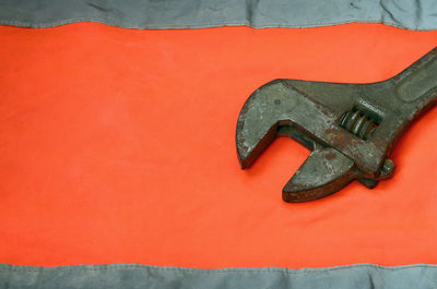 High angle view of old metallic wrench on orange textile