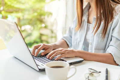 Midsection of woman working with coffee cup